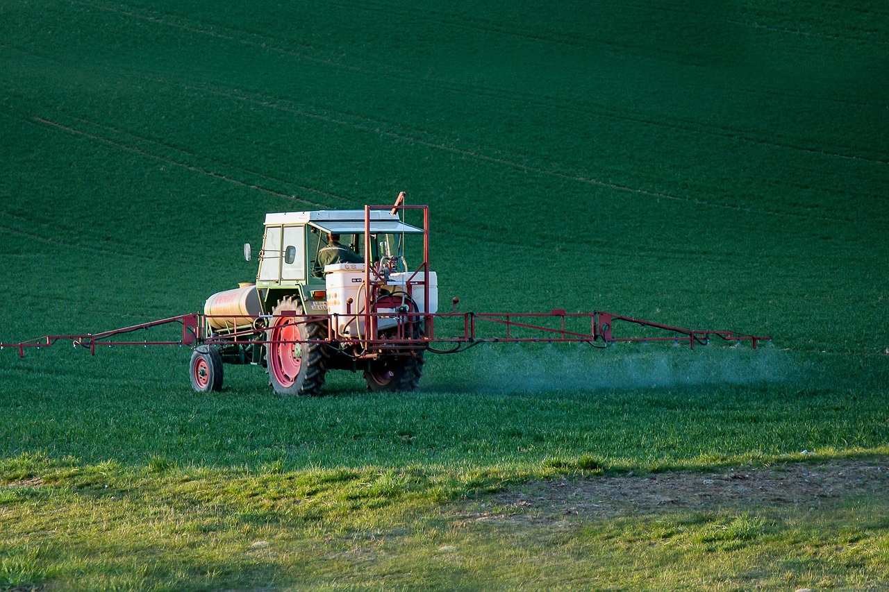 Tracteur pulvérisant des produits phytosanitaires dans un champ agricole.